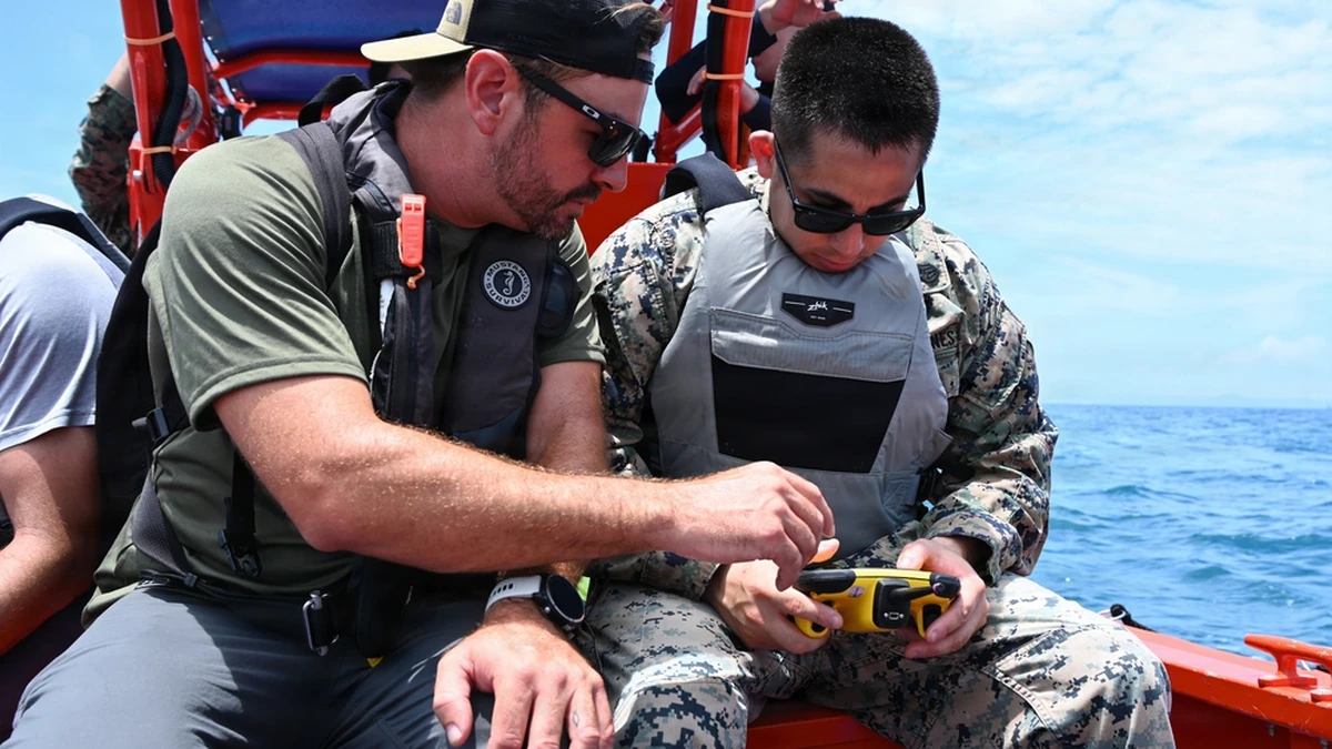 U.S. Marine Corps staff sergeant holding a FORT Robotics remote controller beside a Department of Navy civilian in Okinawa.