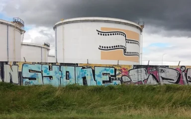 Storage tanks at the Feyzin oil refinery in France beneath dark clouds.