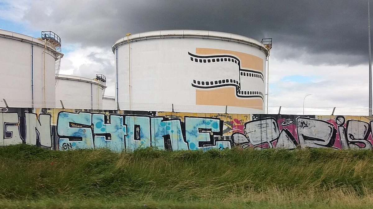 Storage tanks at the Feyzin oil refinery in France beneath dark clouds.