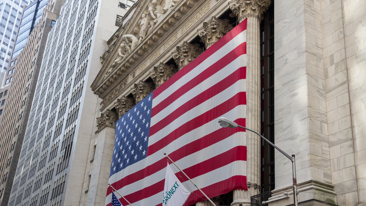 New York Stock Exchange building on Wall Street with a large U.S. flag.