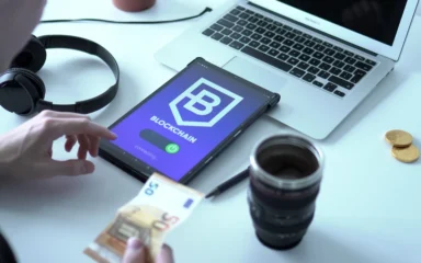 Tablet displaying a blockchain interface beside a laptop and euro banknotes.