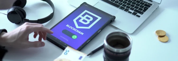 Tablet displaying a blockchain interface beside a laptop and euro banknotes.