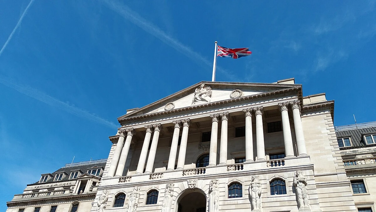 The Bank of England building in London beneath a blue sky with a Union flag flying above it.