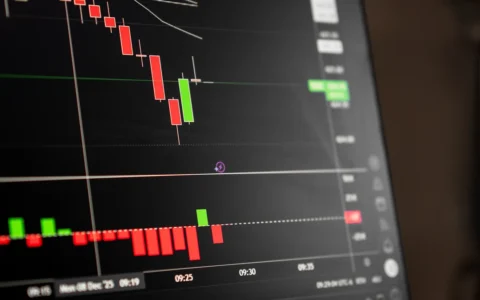 Close-up of a digital screen displaying red and green stock-market candlestick charts.