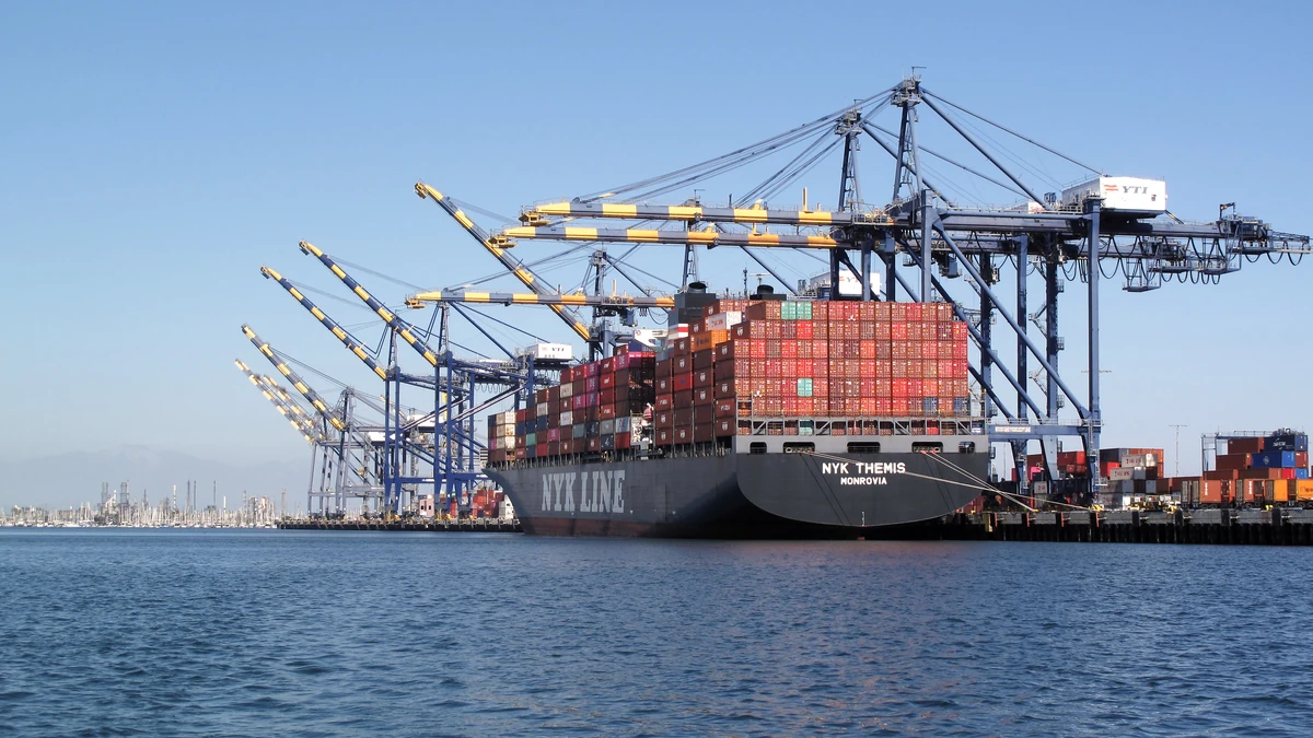 Container ship NYK Themis docked at the Port of Los Angeles with cargo containers and cranes.