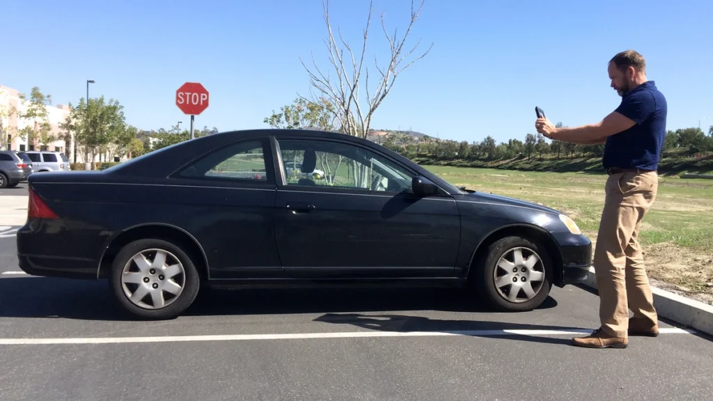 Auto damage appraiser photographing a car during a vehicle condition inspection.