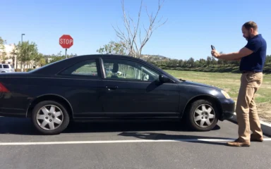 Auto damage appraiser photographing a car during a vehicle condition inspection.