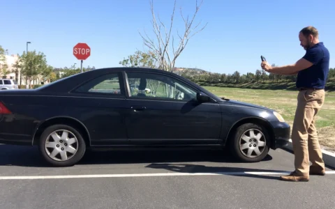 Auto damage appraiser photographing a car during a vehicle condition inspection.