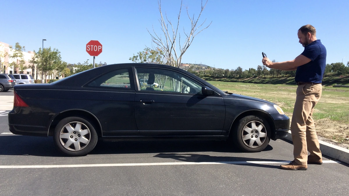 Auto damage appraiser photographing a car during a vehicle condition inspection.
