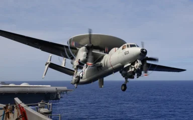 A U.S. Navy E-2C Hawkeye aircraft taking off from USS Kitty Hawk at sea.