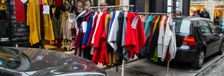 Clothing racks displayed outside a shop on a Paris street.