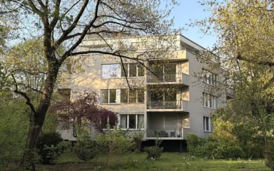 Modernist residential building in Berlin's Hansaviertel surrounded by trees and landscaped grounds.