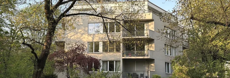 Modernist residential building in Berlin's Hansaviertel surrounded by trees and landscaped grounds.
