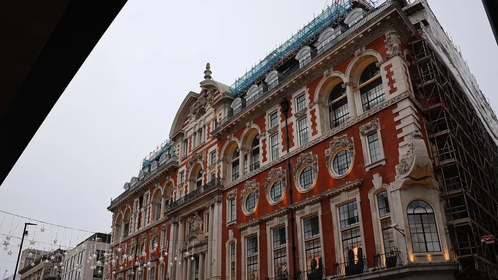 Oxford Street in London with shops and an ornate red-brick building.