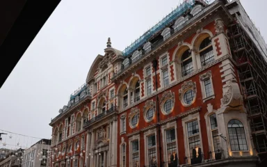 Oxford Street in London with shops and an ornate red-brick building.