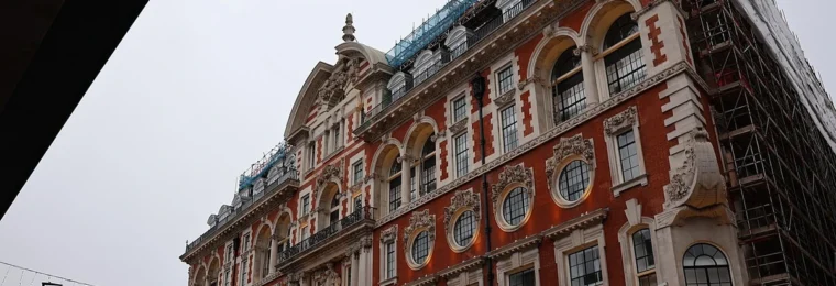 Oxford Street in London with shops and an ornate red-brick building.