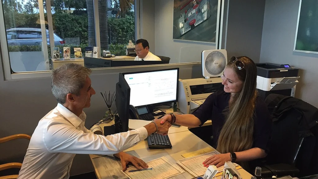 Two people shake hands inside a Group 1 Automotive sales and finance office.