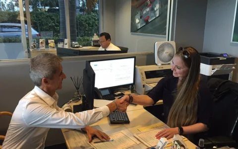 Two people shake hands inside a Group 1 Automotive sales and finance office.