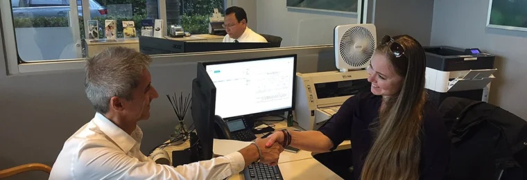 Two people shake hands inside a Group 1 Automotive sales and finance office.