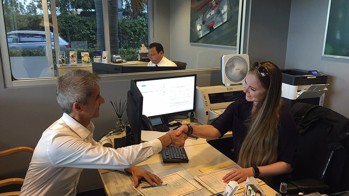 Two people shake hands inside a Group 1 Automotive sales and finance office.