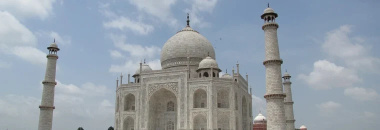 The Taj Mahal in Agra, India, beneath a partly cloudy sky.