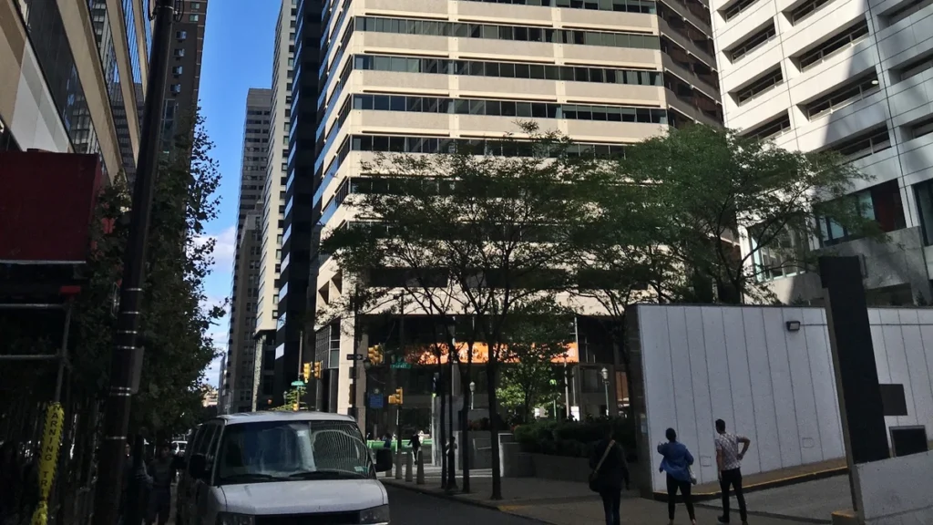 Street-level view of 1835 Market Street in Philadelphia, with the office tower, pedestrians and a vehicle visible.