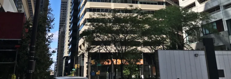 Street-level view of 1835 Market Street in Philadelphia, with the office tower, pedestrians and a vehicle visible.