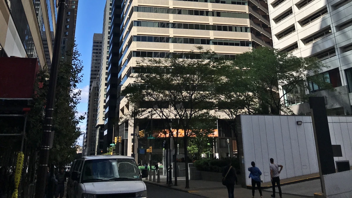 Street-level view of 1835 Market Street in Philadelphia, with the office tower, pedestrians and a vehicle visible.