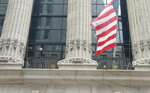 The Broad Street facade of the New York Stock Exchange building in Manhattan with a U.S. flag above the entrance.