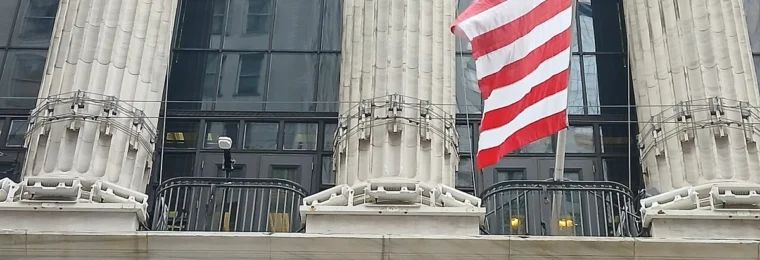 The Broad Street facade of the New York Stock Exchange building in Manhattan with a U.S. flag above the entrance.