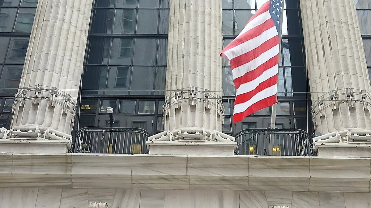 The Broad Street facade of the New York Stock Exchange building in Manhattan with a U.S. flag above the entrance.