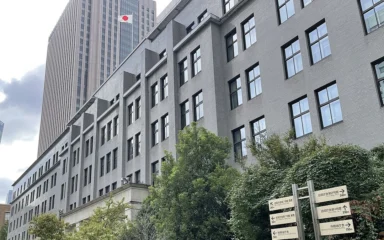 Japan's Ministry of Finance building in Tokyo, with the Japanese flag visible on the tower behind it.