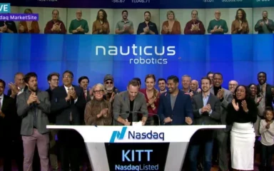 Nauticus Robotics team at a Nasdaq MarketSite event with company branding displayed behind them.