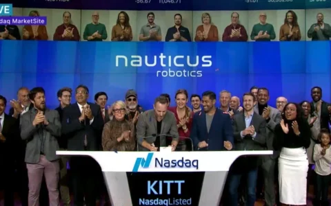 Nauticus Robotics team at a Nasdaq MarketSite event with company branding displayed behind them.