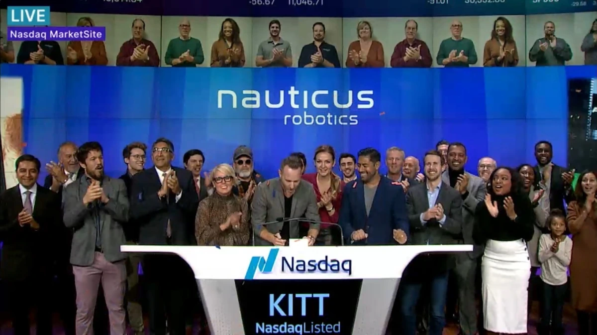 Nauticus Robotics team at a Nasdaq MarketSite event with company branding displayed behind them.