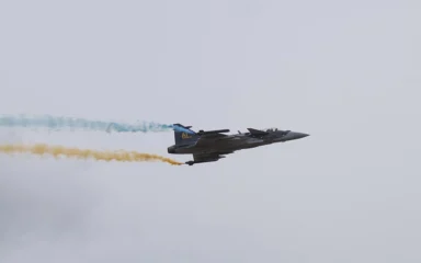 Gripen E 39-6002 flying during Flygdagarna 2026 in Malmen, Linköping, trailing blue and yellow smoke.