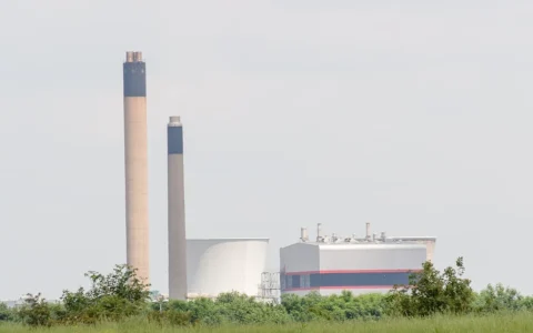 Slough Trading Estate in Slough, England, with industrial buildings and tall chimneys viewed across grassland.