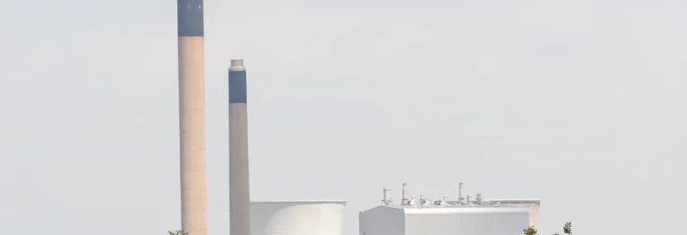 Slough Trading Estate in Slough, England, with industrial buildings and tall chimneys viewed across grassland.