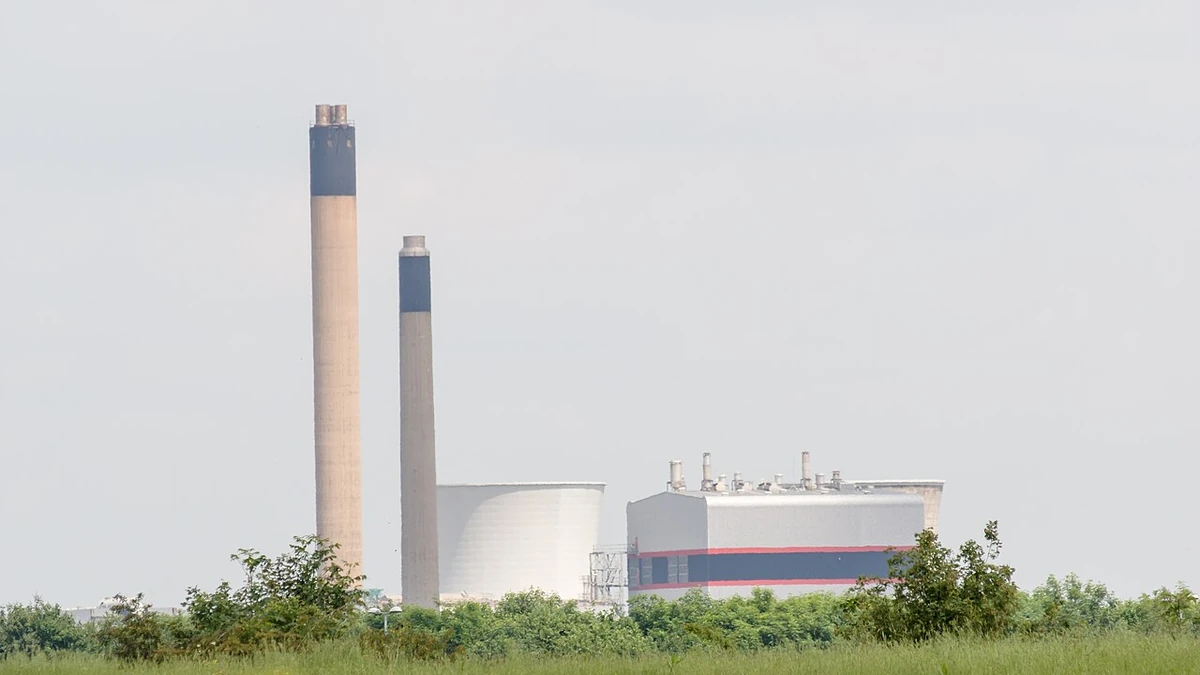 Slough Trading Estate in Slough, England, with industrial buildings and tall chimneys viewed across grassland.