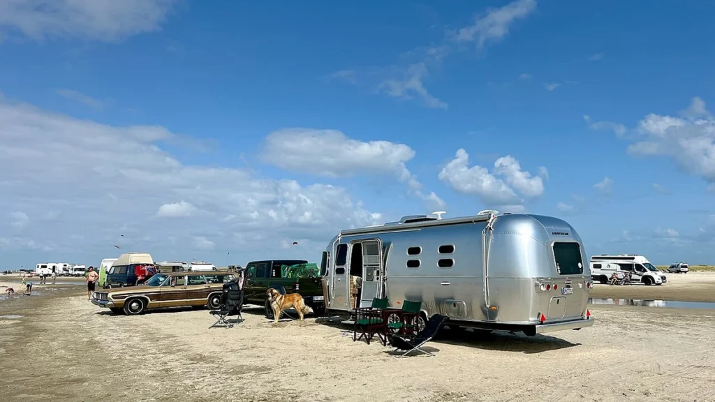 Silver Airstream travel trailer parked on Lakolk Beach on Rømø island, Denmark.