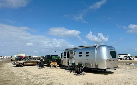 Silver Airstream travel trailer parked on Lakolk Beach on Rømø island, Denmark.