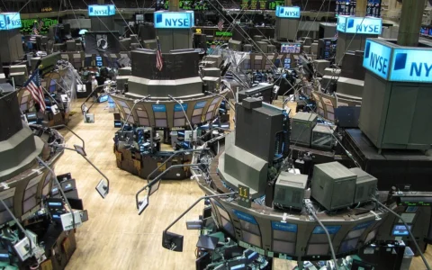 New York Stock Exchange trading floor with NYSE signs and trading stations.