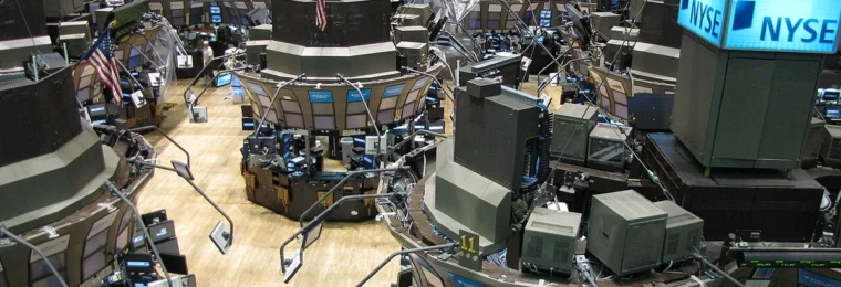 New York Stock Exchange trading floor with NYSE signs and trading stations.