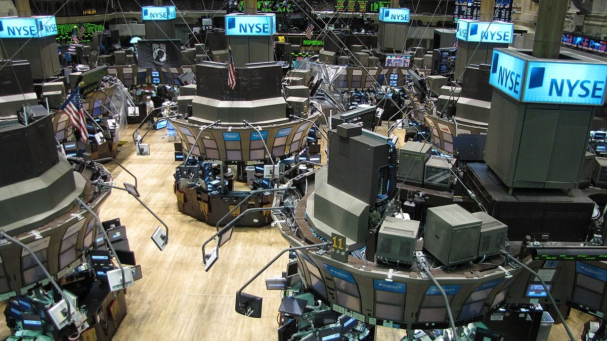 New York Stock Exchange trading floor with NYSE signs and trading stations.