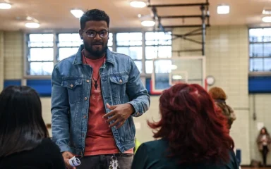 A man speaks with attendees seated at a table during an MTA job fair in East Harlem, New York.