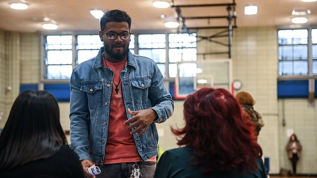 A man speaks with attendees seated at a table during an MTA job fair in East Harlem, New York.
