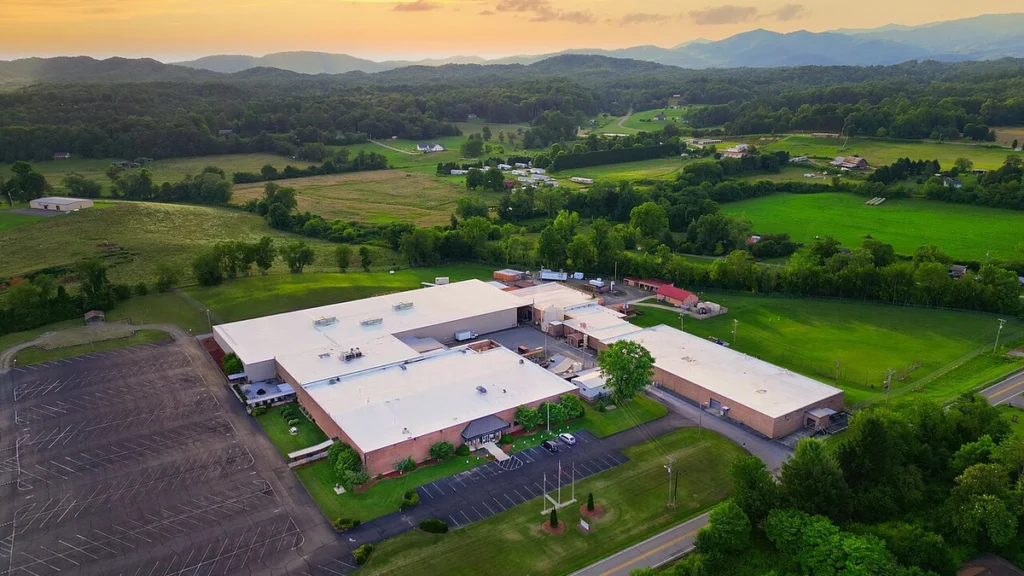 Aerial view of a Moog Inc. manufacturing plant in Peachtree, North Carolina, surrounded by green hills.
