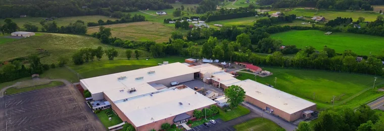 Aerial view of a Moog Inc. manufacturing plant in Peachtree, North Carolina, surrounded by green hills.