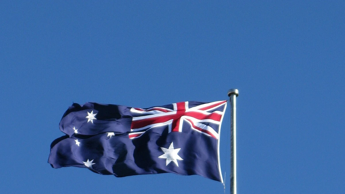 Australian flag flying on a flagpole against a blue sky.