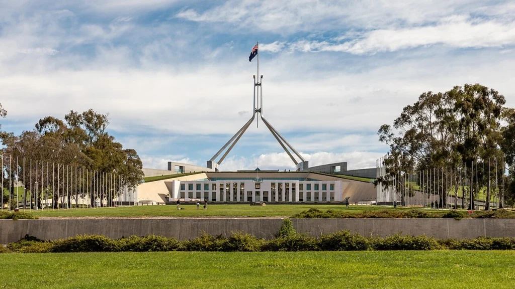 Front view of Australian Parliament House in Canberra, with an Australian flag flying above it.